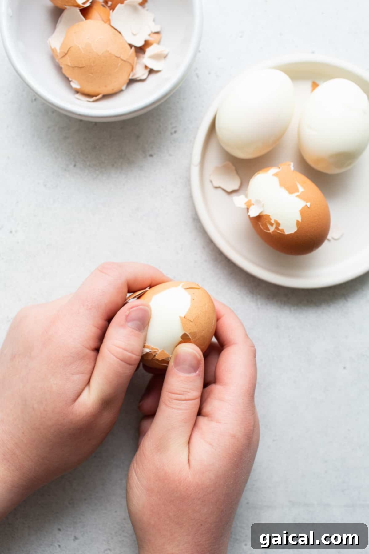 Effortless Peeling for Air Fryer Eggs Hands gently peeling the shell from a freshly air-fried hard boiled egg, demonstrating the ease of the process.