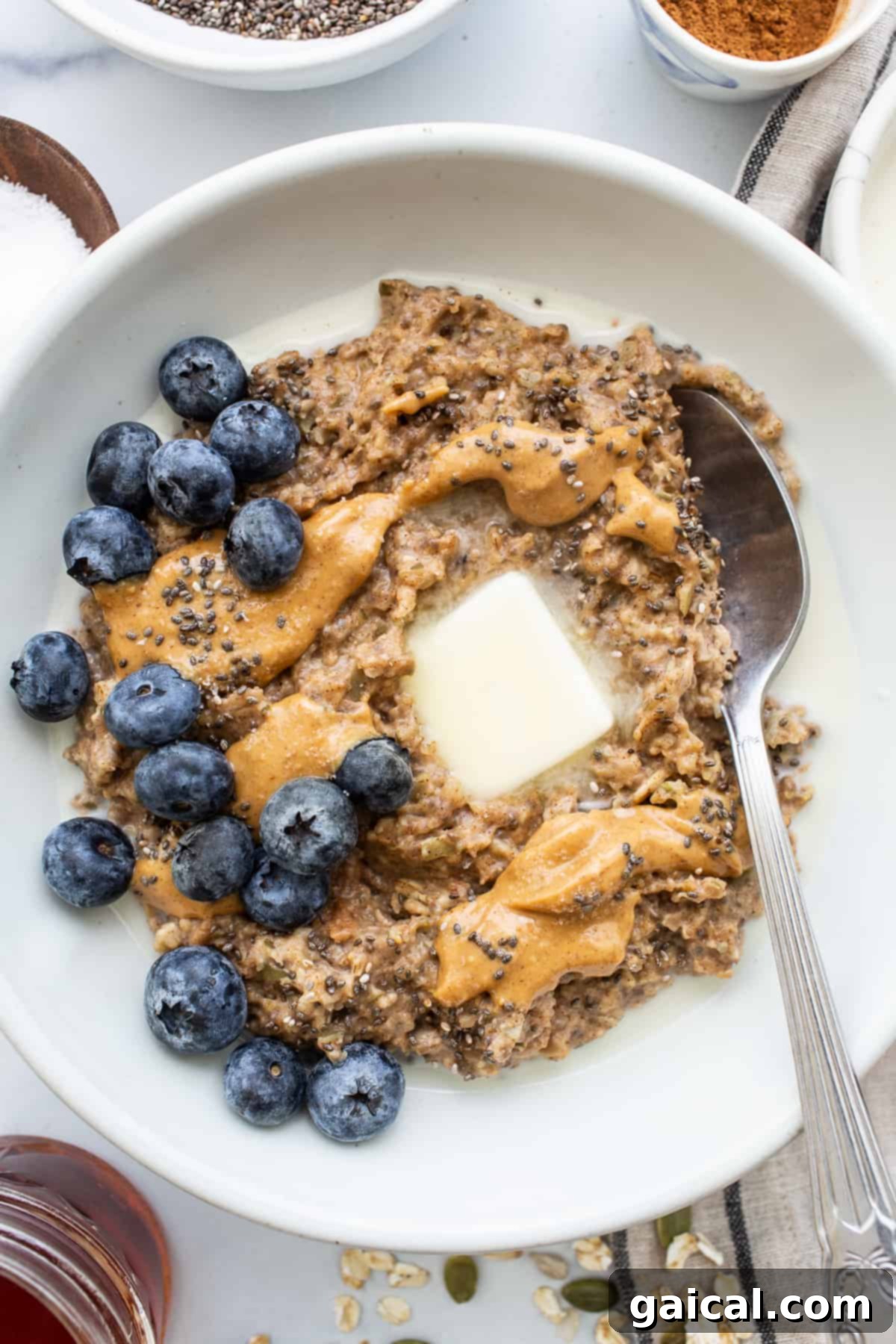 Sunrise Comfort Bowl 2 Porridge in a bowl topped with fresh blueberries, a drizzle of nut butter, and a sprinkle of seeds.