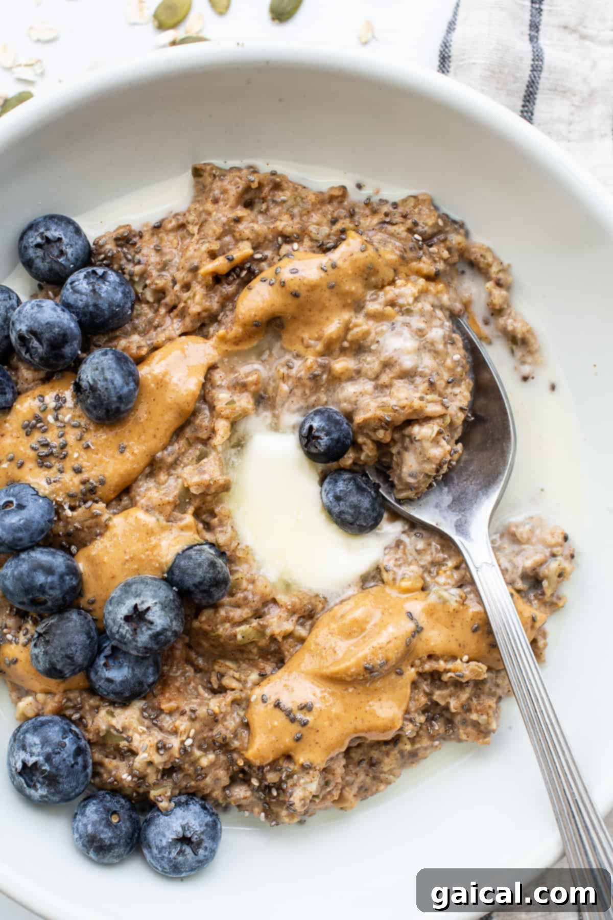 Sunrise Comfort Bowl 8 A bowl of creamy porridge generously topped with fresh berries, a rich swirl of nut butter, and a sprinkle of seeds.