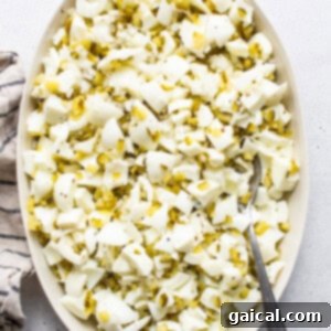 Devilishly Good Egg Spread 6 Chopped egg whites mixed with spices, pickles, and onion in a white bowl, with a spoon.
