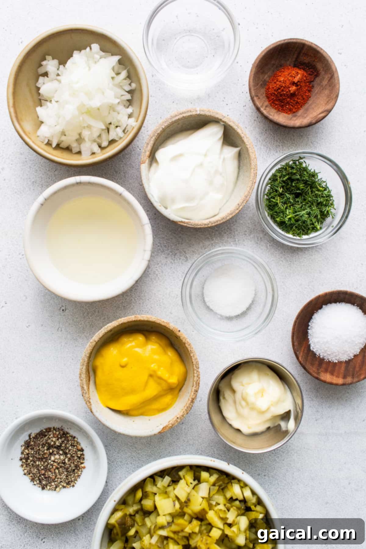 Key ingredients laid out and ready for making deviled egg salad. Individual bowls showcasing the fresh, prepared ingredients for deviled egg salad, including finely diced dill pickles, minced white onion, creamy Greek yogurt, and vibrant yellow mustard.