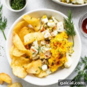 Devilishly Good Egg Spread 9 A bowl of deviled egg salad next to a generous pile of crispy potato chips, ready for dipping and enjoying.