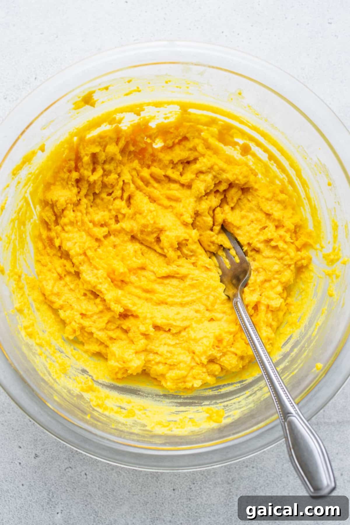 Creamy egg yolks, meticulously prepared for the deviled egg salad. A close-up shot of the creamy and smooth egg yolk mixture in a white bowl, meticulously blended with a fork, ready for the next step in the deviled egg salad preparation.