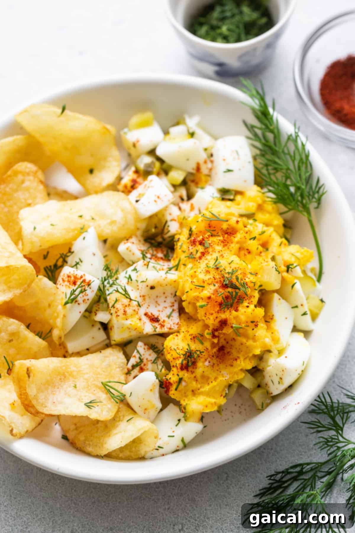 Close-up view of deviled egg salad, garnished with fresh dill. A close-up of a generous bowl of deviled egg salad, beautifully garnished with a vibrant sprinkle of fresh dill and paprika, ready for serving.