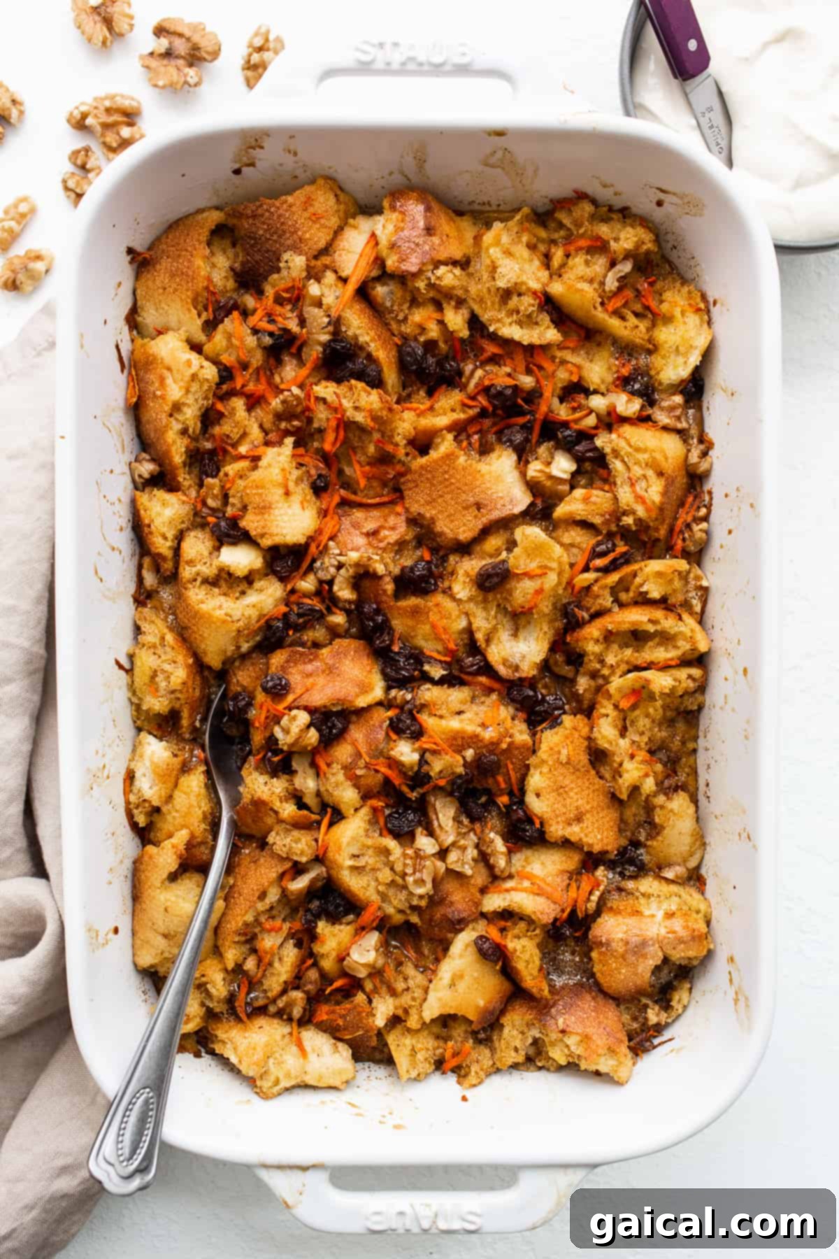 A spoon in a casserole dish of carrot cake French toast casserole.