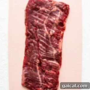 Mastering Skirt Steak Cooking 10 A piece of beef on a cutting board, being pounded with a meat tenderizer.