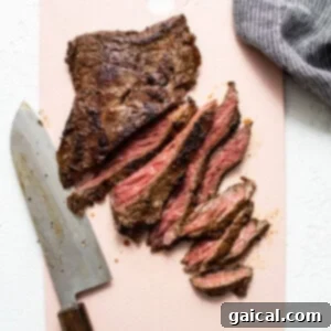 Mastering Skirt Steak Cooking 14 A piece of grilled steak being sliced on a pink cutting board.