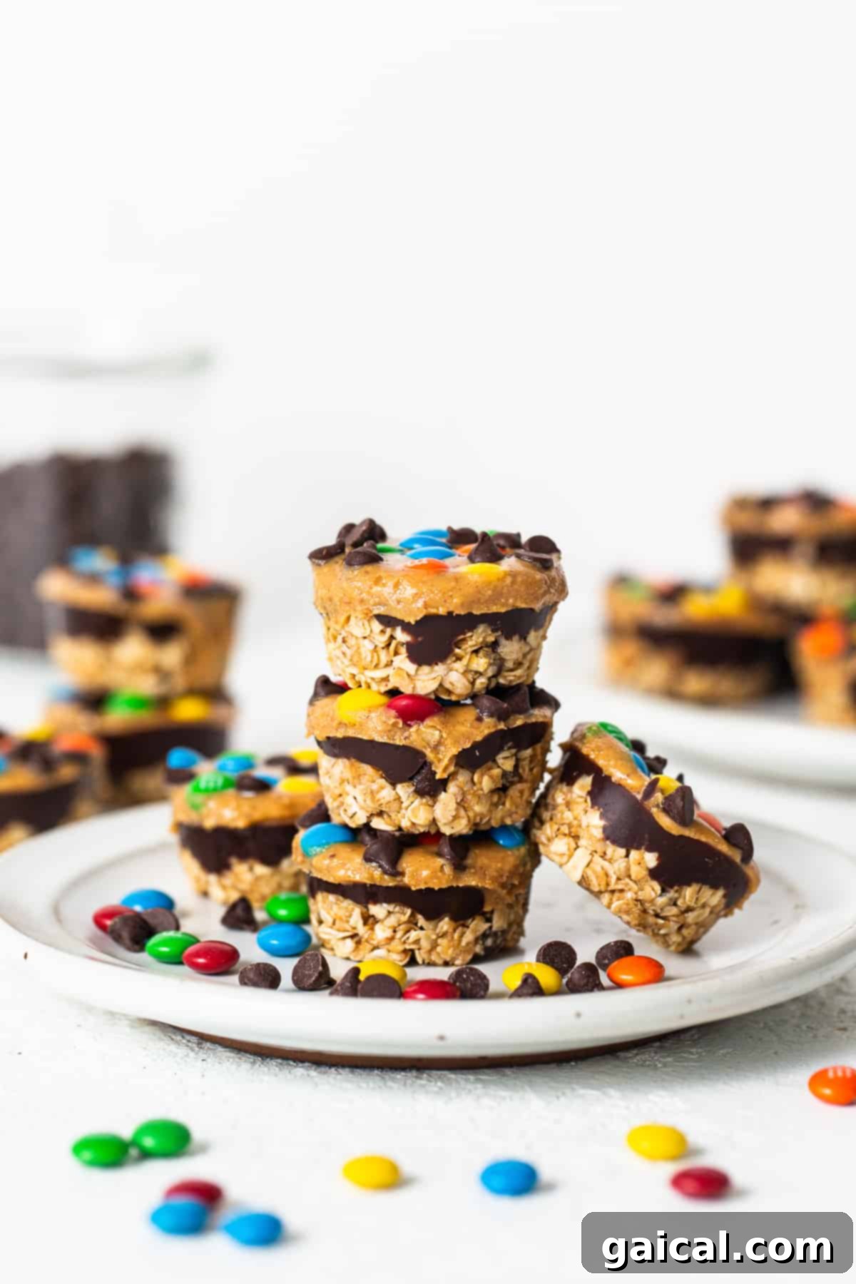 A stack of perfectly prepared monster cookie oat cups, ready to be stored or enjoyed, on a white plate.