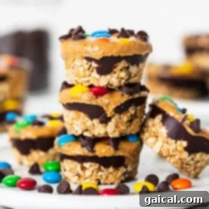 Monster cookie oat cups stacked invitingly on a white plate, showcasing their layers and colorful toppings.
