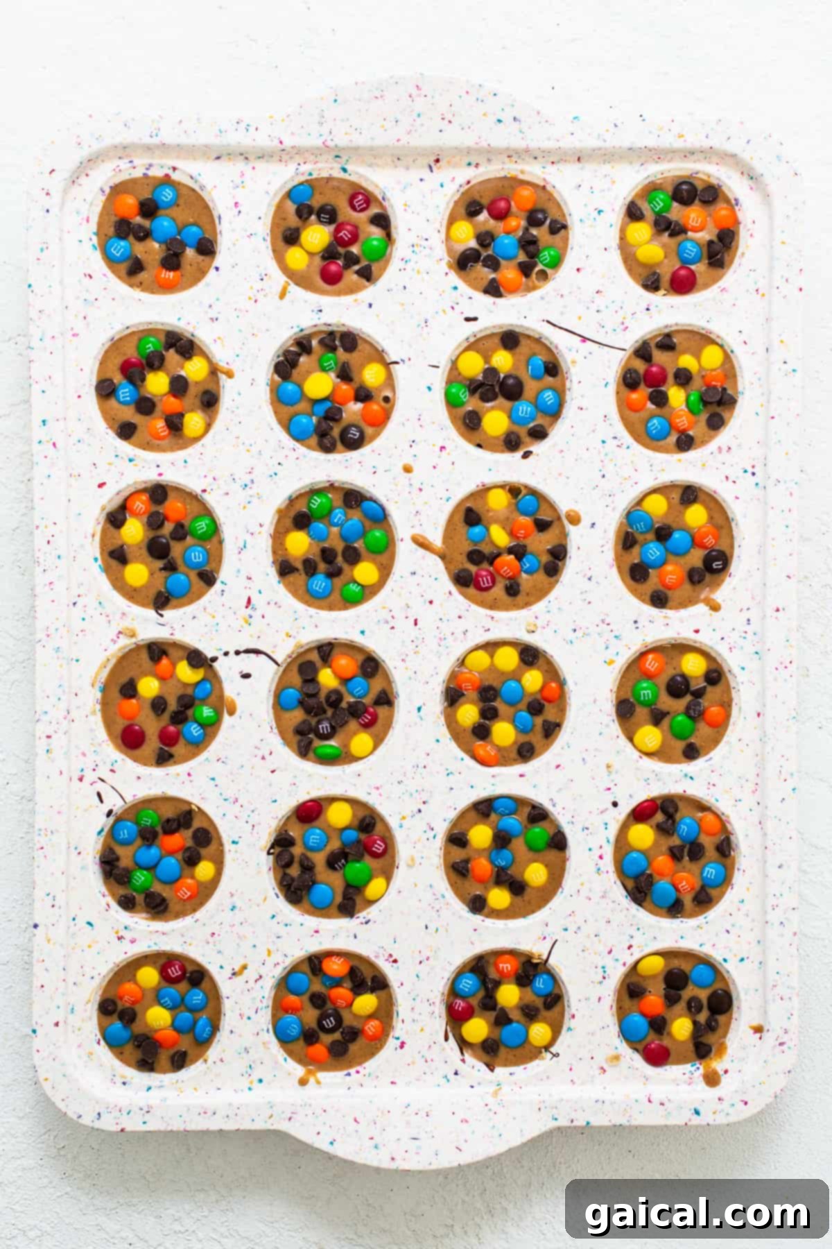 Perfectly formed monster cookie oat cups sitting in a mini muffin tin, ready to be chilled.