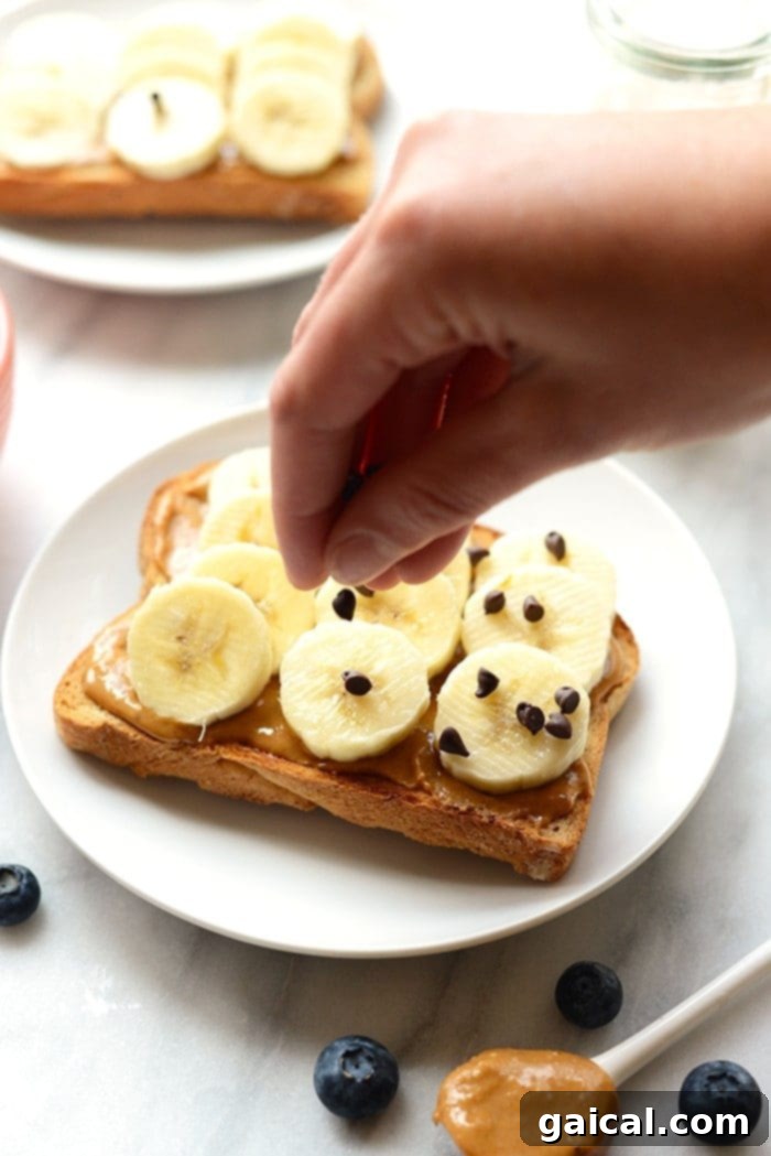 Peanut Butter Banana Toast: A Sweet and Satisfying Treat A beautifully prepared peanut butter toast, generously topped with banana slices, a drizzle of golden honey, and a scattering of mini chocolate chips on a white plate.