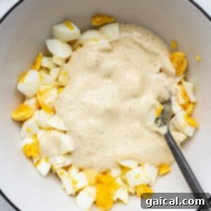The Secret to Irresistible Egg Salad 7 Combining egg salad ingredients in a bowl, demonstrating the creamy dressing coating the chopped eggs evenly.