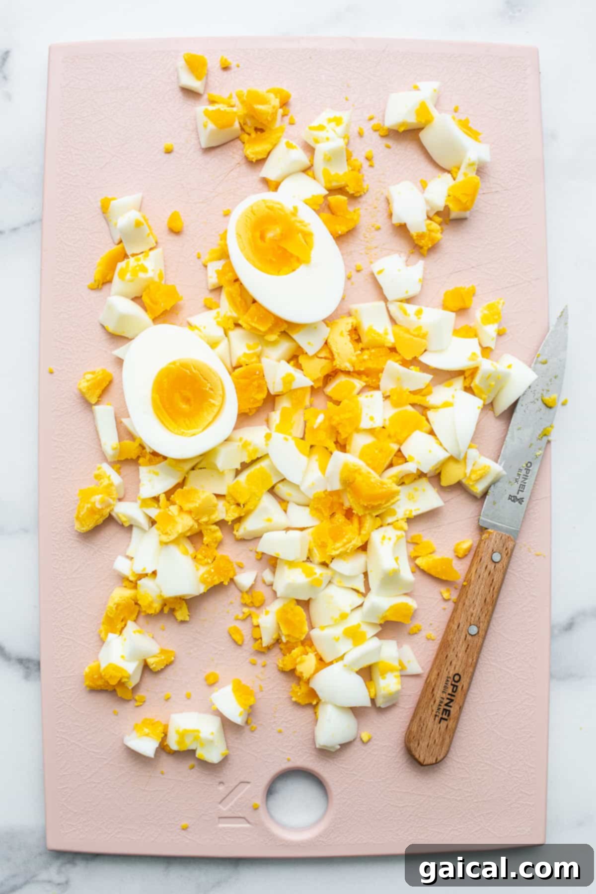 Classic egg salad is made with perfectly cooked hard-boiled eggs and a yummy sauce. Perfectly chopped hard-boiled eggs arranged on a cutting board, ready for mixing into a delicious egg salad.
