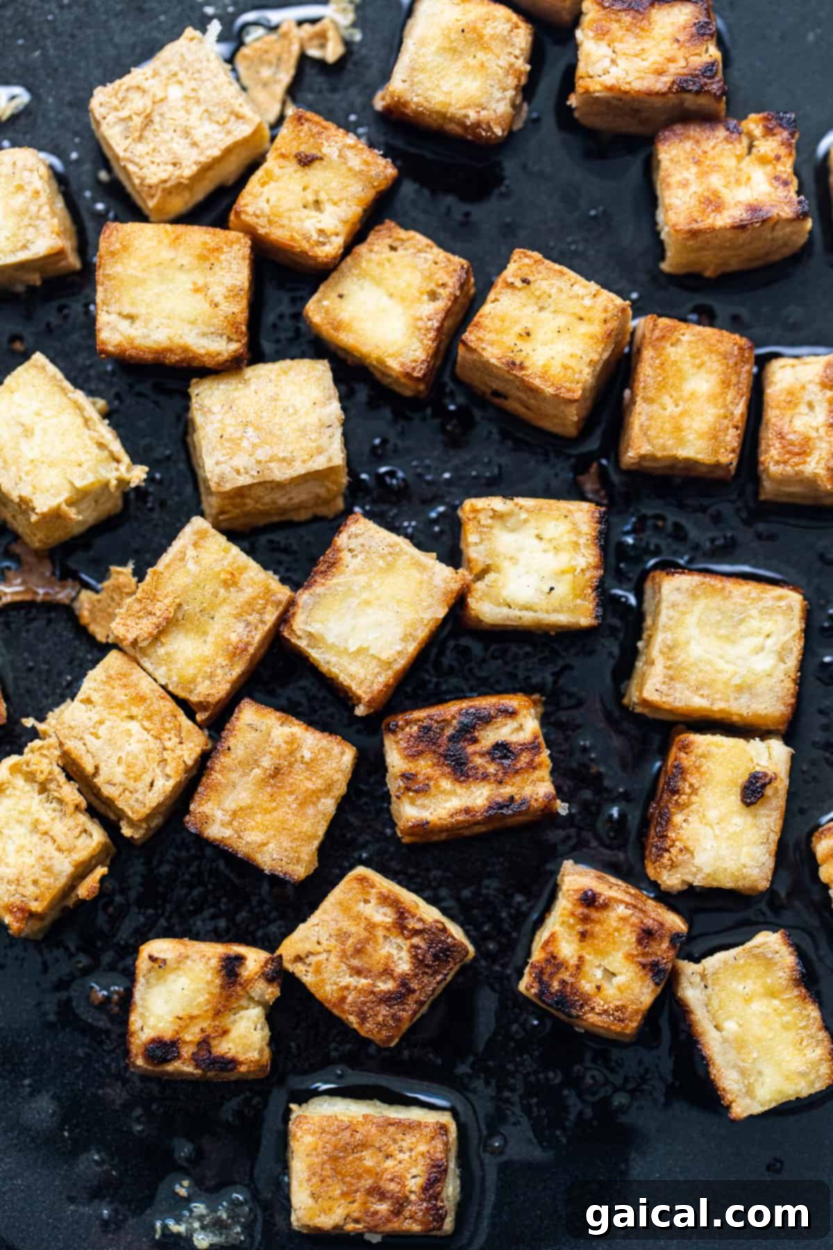 Perfectly golden and crispy pan-fried tofu cubes resting in a skillet, ready to be served.