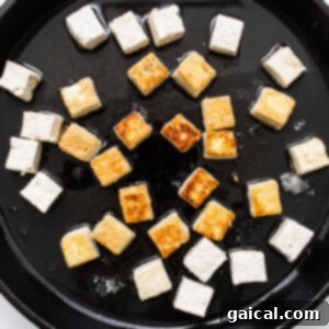 Tofu in a skillet on a white surface.