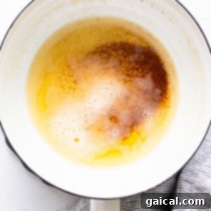 Butter browning in a small saucepan, showing a rich, amber color and golden sediment at the bottom.
