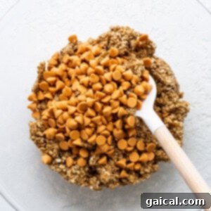Finished cookie batter with quick oats and butterscotch chips in a mixing bowl.
