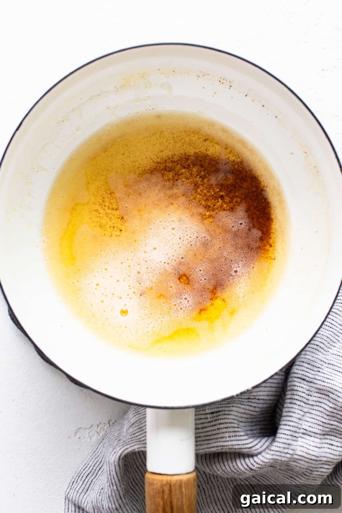 A saucepan on a stove with butter browning, showing golden-brown specks at the bottom.