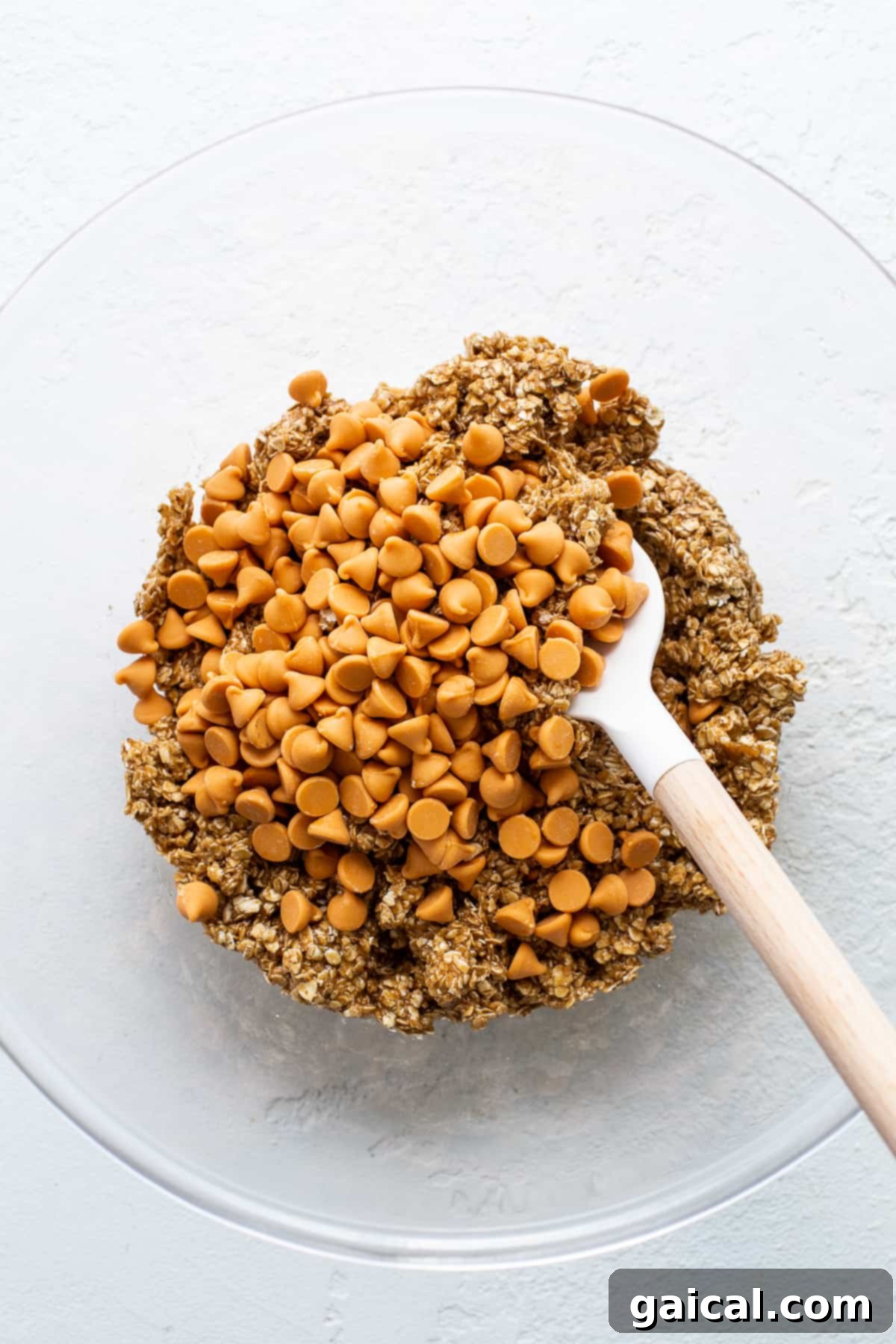 Bowl of cookie dough showing quick oats, butterscotch chips, and brown butter.