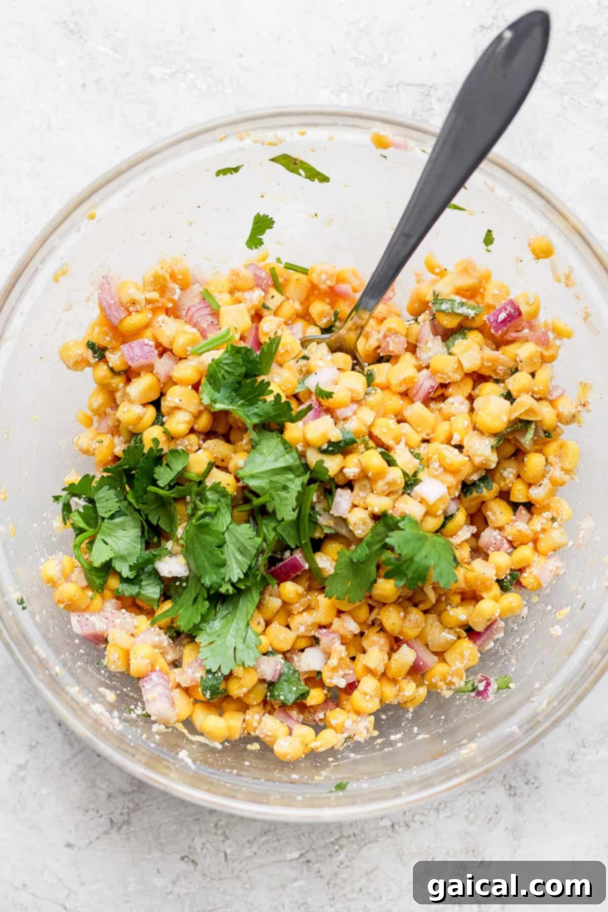 Set It And Forget It Carnitas Burrito Bowls 7 A glass bowl featuring Mexican corn salad with slow cooker carnitas, artfully layered.