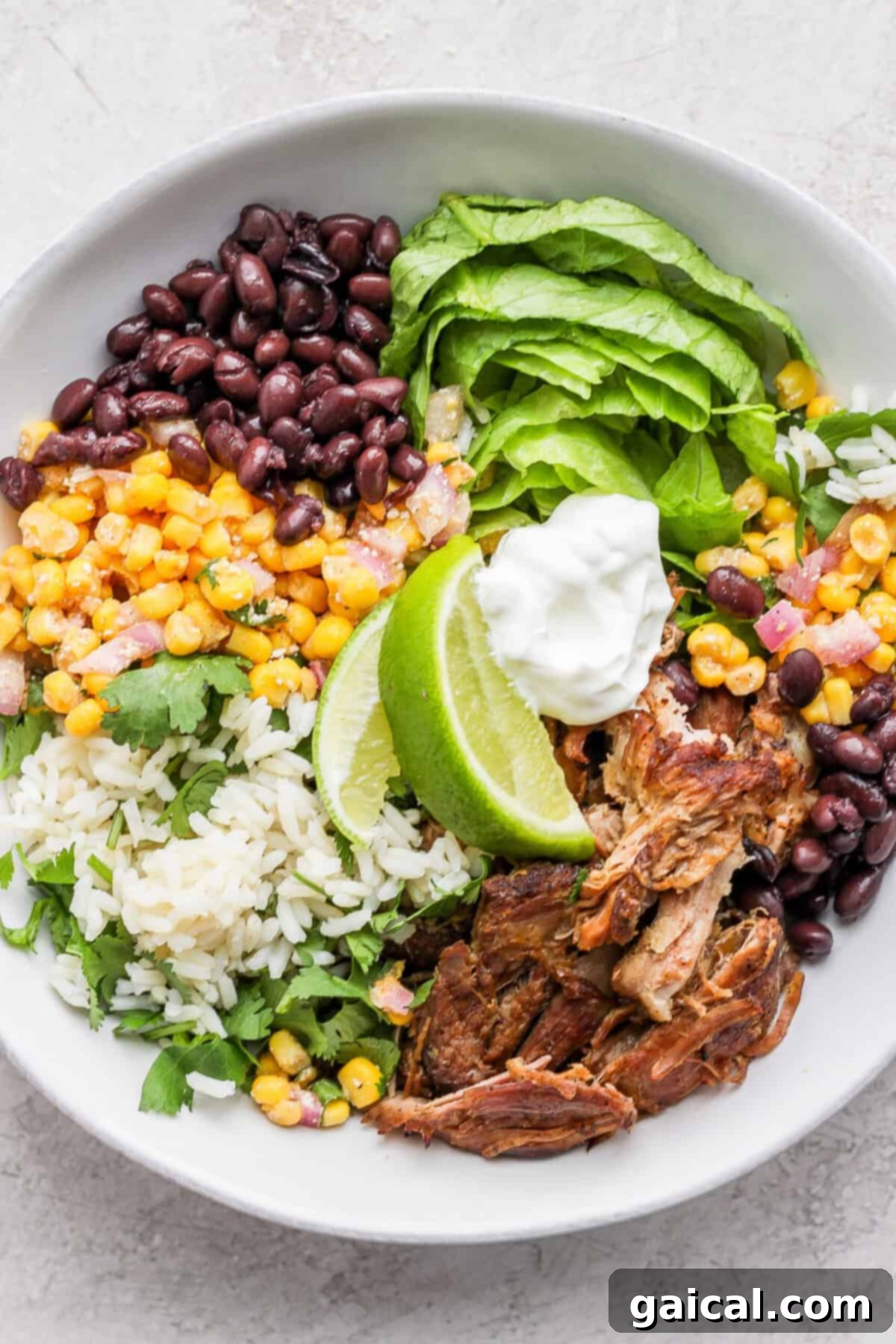 Set It And Forget It Carnitas Burrito Bowls 8 A hearty bowl of slow cooker carnitas salad, featuring corn, black beans, and a dollop of sour cream or Greek yogurt.