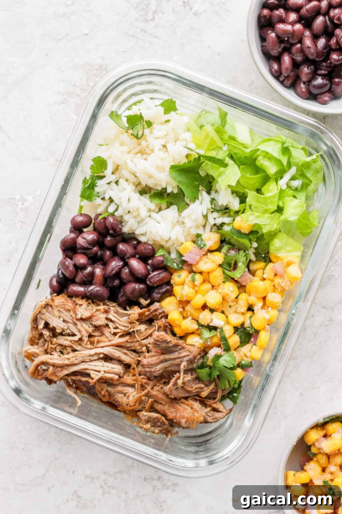 Set It And Forget It Carnitas Burrito Bowls 9 A slow cooker carnitas meal, perfectly portioned with rice, beans, and corn, served in a practical glass container for meal prep.