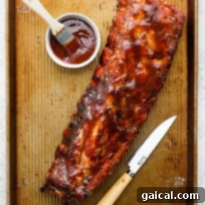 Grilled BBQ ribs on a tray with a knife, showing the meat pulling back from the bones.