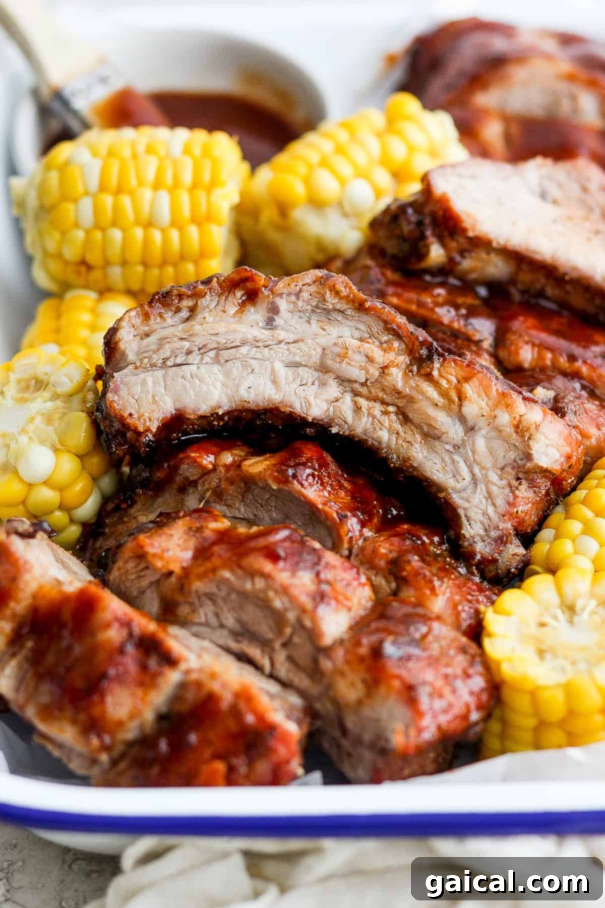 Plate of perfectly grilled ribs served with corn on the cob, ready for a summer meal.