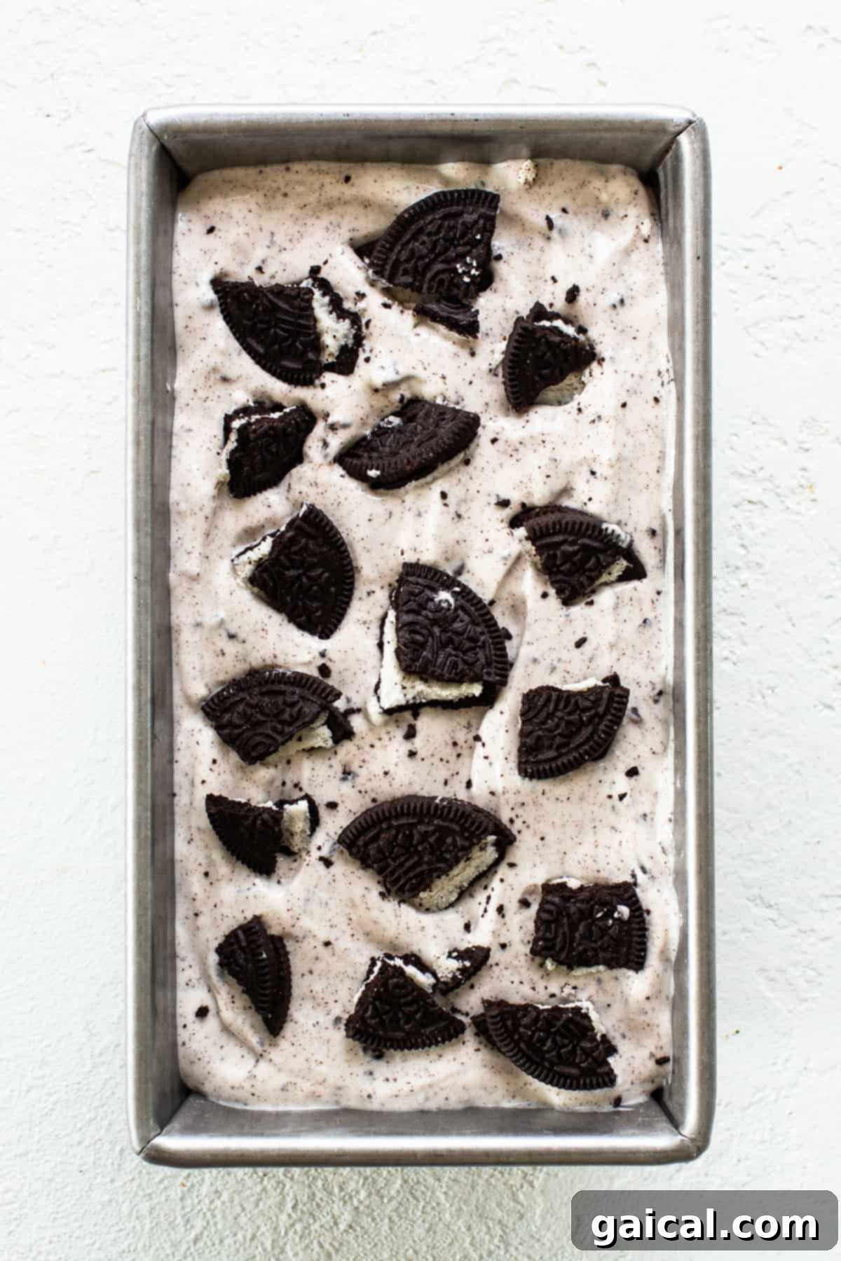 Cookies & Cream Protein Dream 7 Scoopable cottage cheese ice cream setting in a metal loaf pan in the freezer, showing its firm texture.
