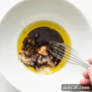Smoky Grilled Portobello Steaks 10 A person is whisking oil into a white bowl, part of the marinade preparation.