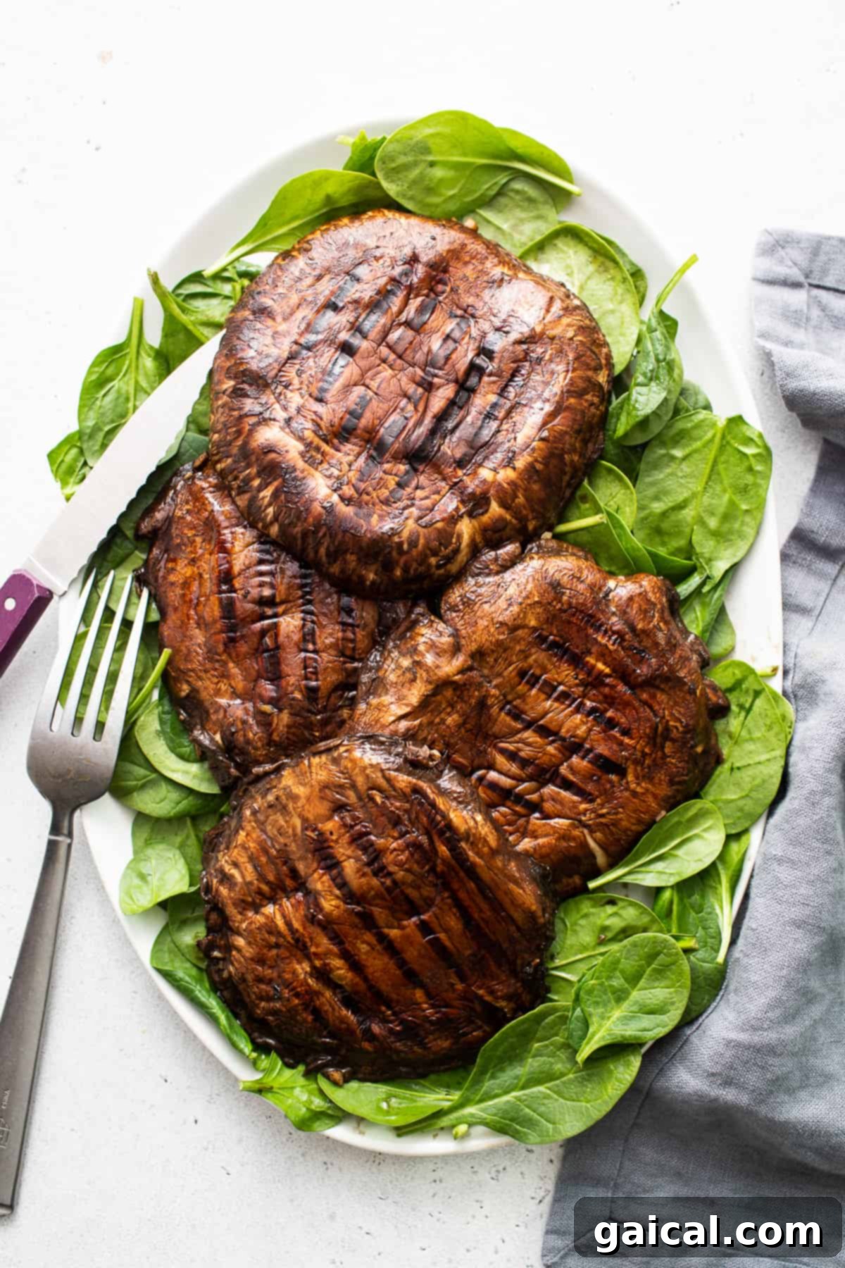 Smoky Grilled Portobello Steaks 7 Two grilled portobello mushrooms artfully arranged on a clean white plate, ready to be served.