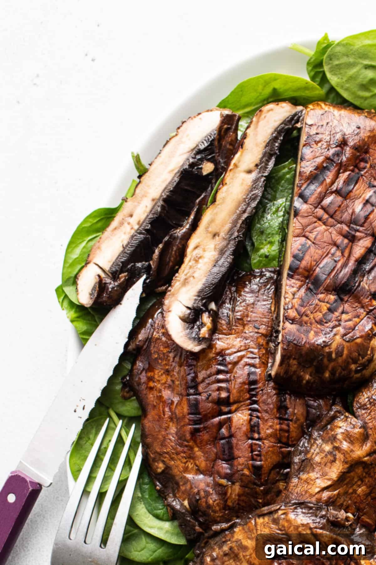 Smoky Grilled Portobello Steaks 8 A perfectly sliced grilled portobello mushroom on a white plate, revealing its juicy interior.