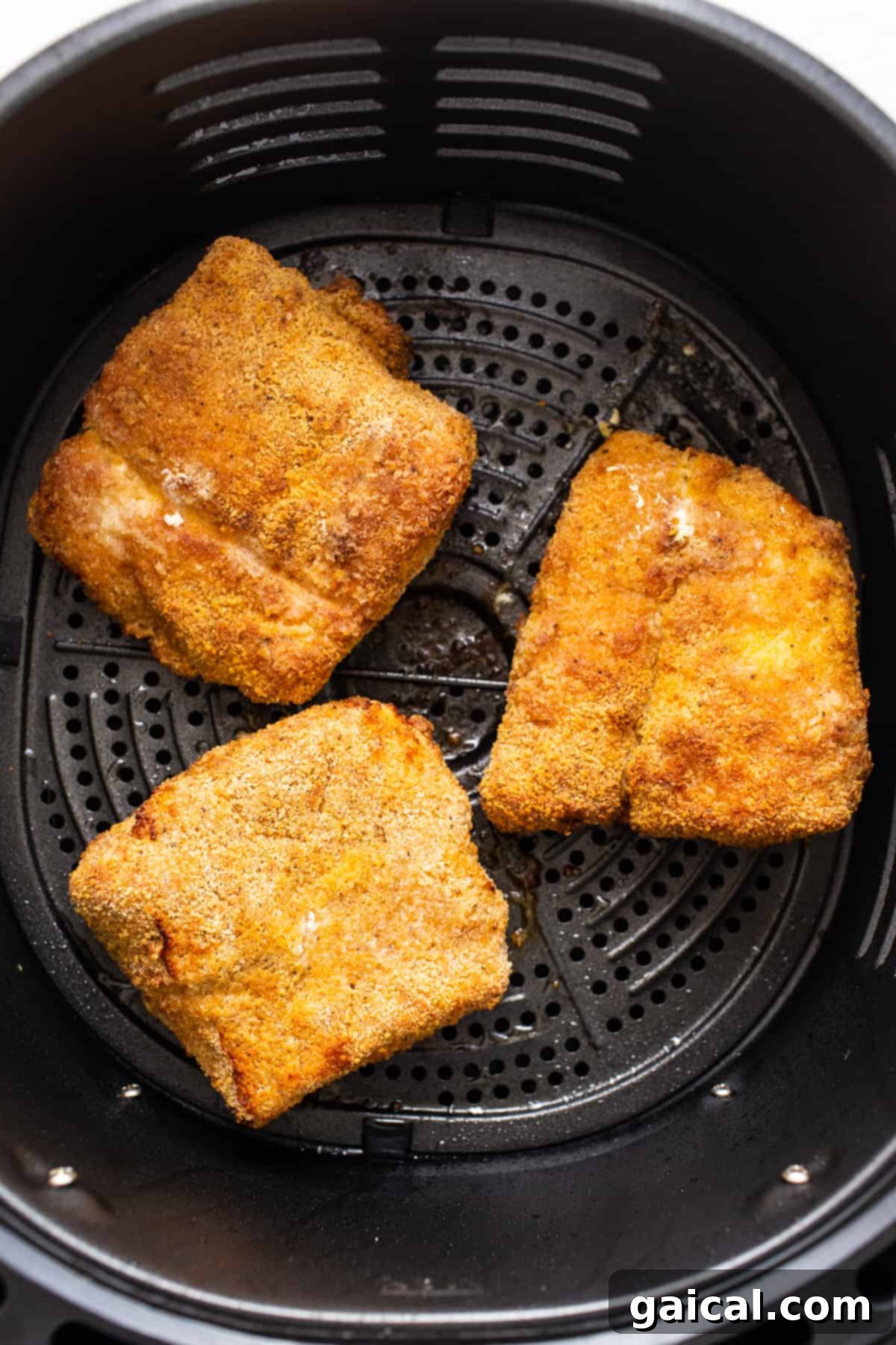 Air Frying Fish for Optimal Crispiness Crispy golden-brown air fryer fish pieces cooking in an air fryer basket.