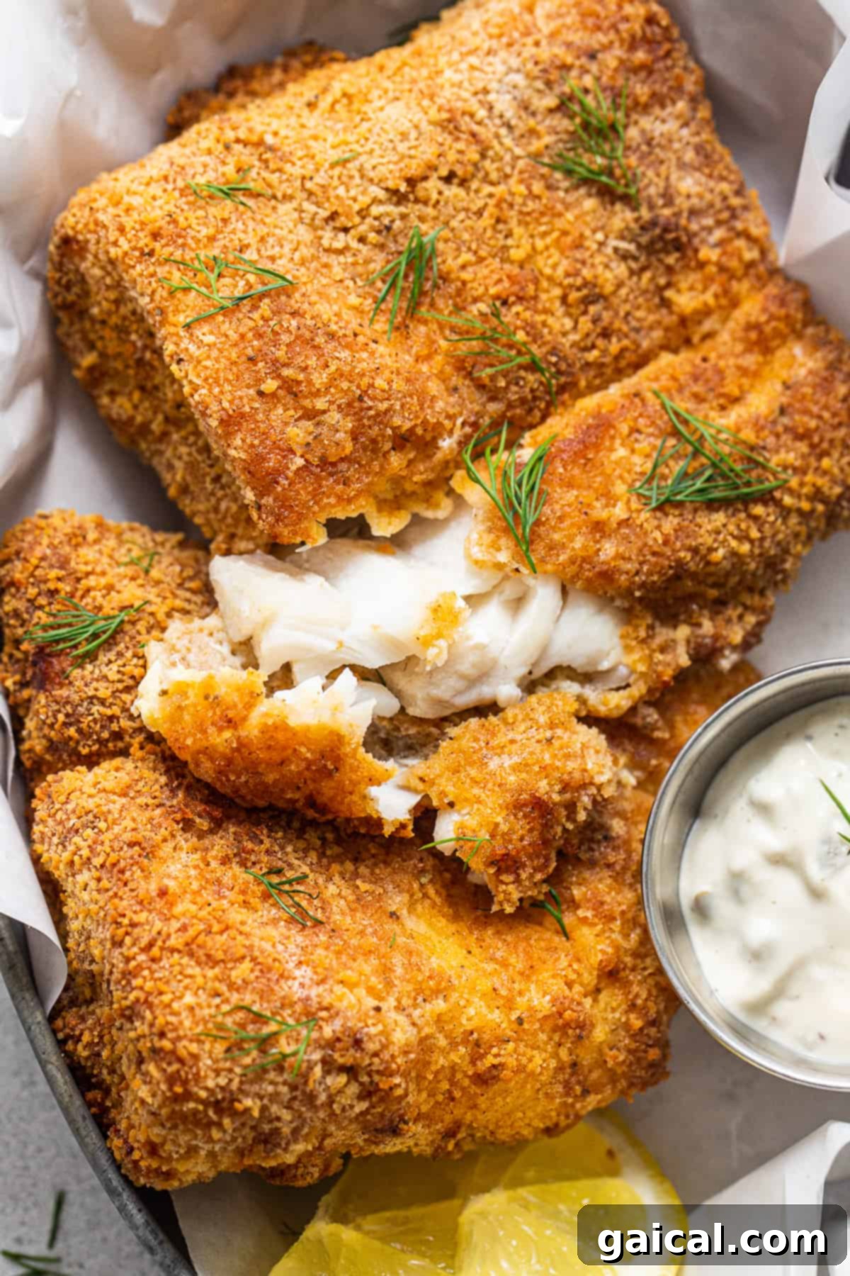 Flaky Air Fryer Fish with Tartar Sauce Flaky air fryer fish pieces resting on a bed of lemon slices, served with a dollop of tartar sauce.