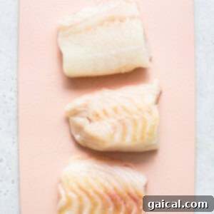 Golden Crunchy Air Fryer Fish Fillets 4 Raw cod filets on a cutting board, ready for preparation.