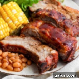A generous plate of tender baby back ribs, alongside baked beans, corn on the cob, and a fresh salad, illustrating a complete and satisfying meal.