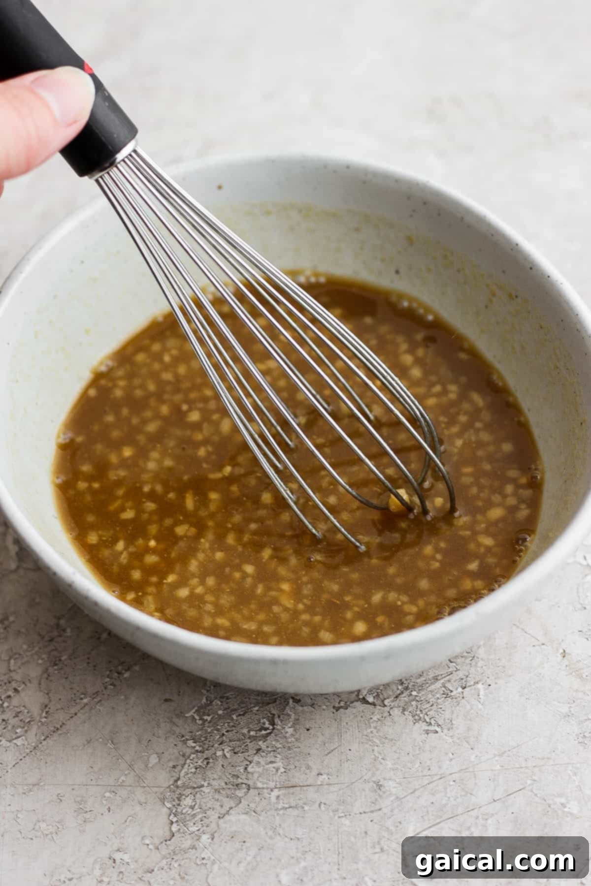 This classic rib marinade recipe is perfectly savory and sweet with only 5 ingredients -- an amazing complement to your baby back ribs. Enjoy! Rib marinade in a bowl with a whisk.