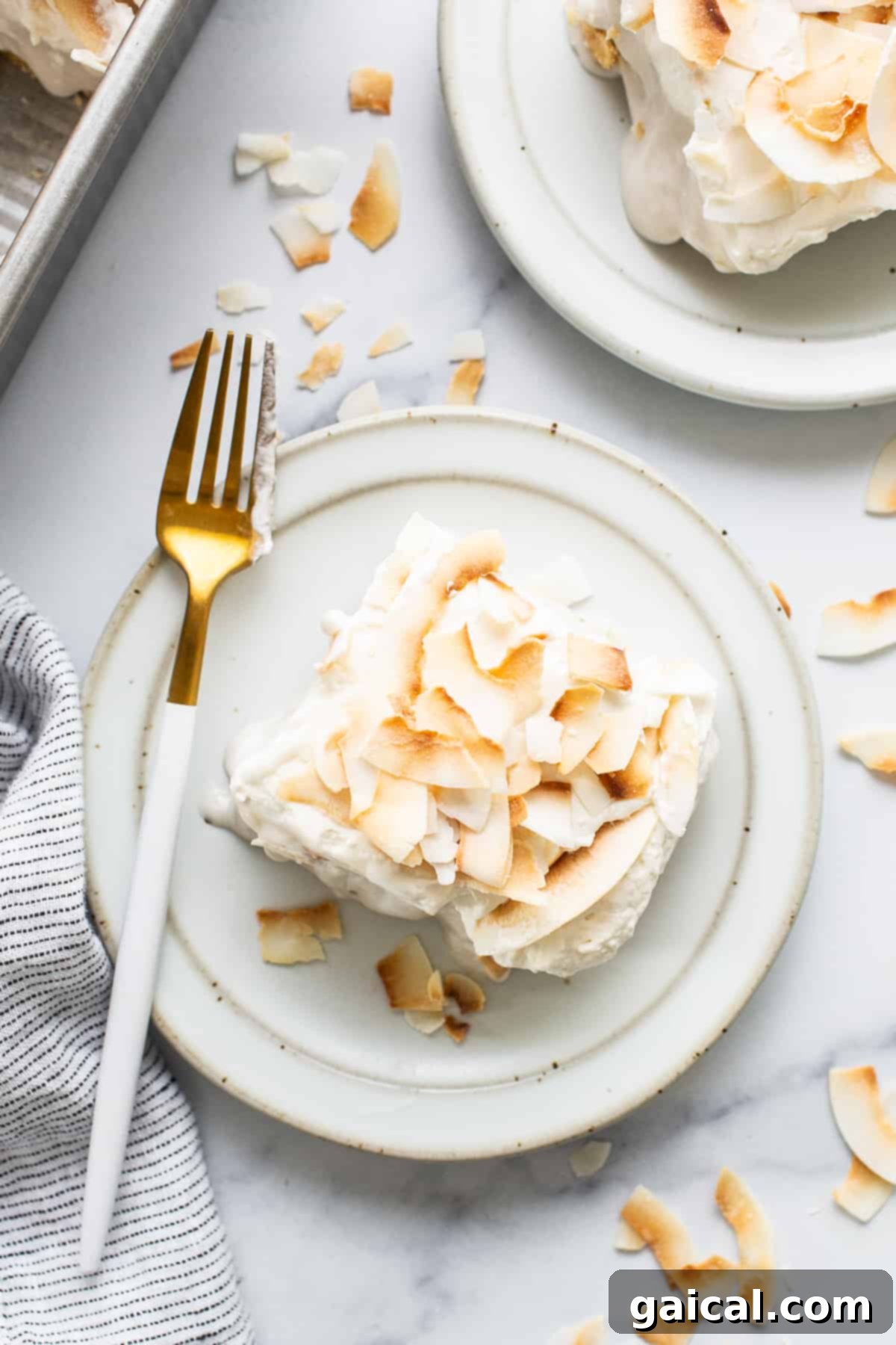 Creamy Coconut Dream Bars 7 A perfect slice of coconut cream pie bar, showcasing the distinct layers, placed on a white plate with a fork.