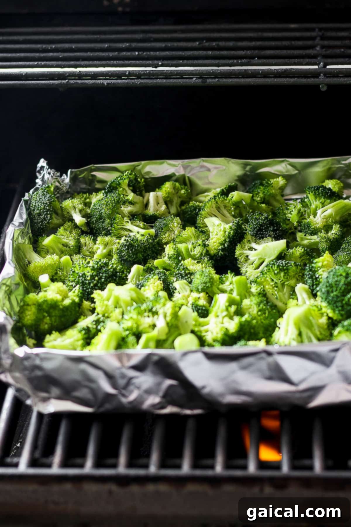 Charred Broccoli Perfection 5 A baking tray filled with fresh green broccoli florets is placed inside a preheated oven, ready for roasting, offering an alternative cooking method to grilling.