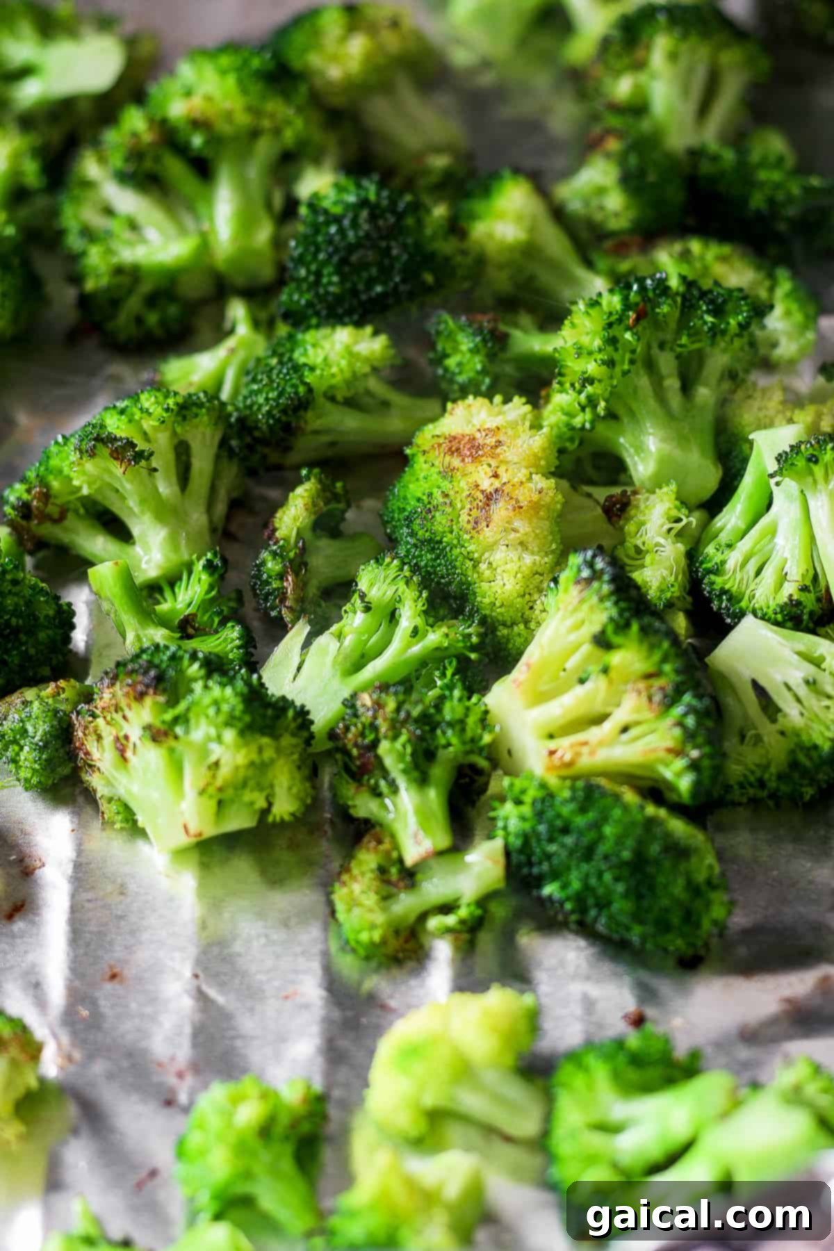 Charred Broccoli Perfection 6 A large head of fresh broccoli, still raw and vibrant green, sits on a piece of aluminum foil, ready for seasoning and preparation before grilling.