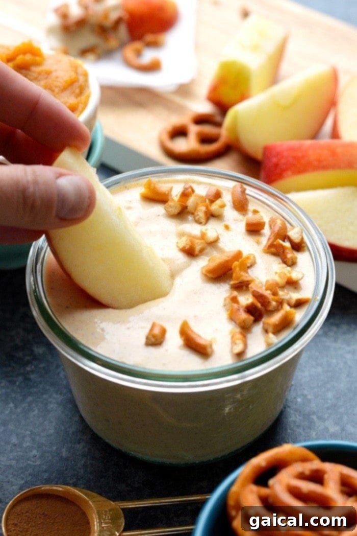 Pumpkin Spice Greek Yogurt Dip 2 Delicious and healthy pumpkin Greek yogurt dip in a bowl, surrounded by apple slices and pretzels, ready for a perfect fall snack.