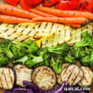 A variety of vibrant, uncooked vegetables beautifully laid out on a cutting board, prepped and ready for grilling.