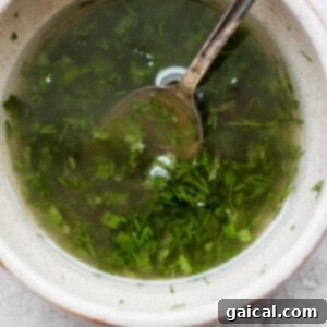 A bowl of fresh herby dressing with a spoon, ready to be used.