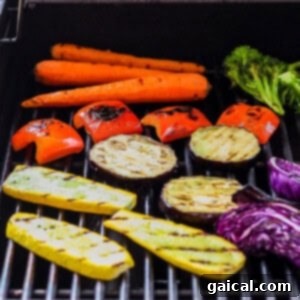 Various vegetables like carrots, broccoli, and other assorted greens cooking on a barbecue grill.