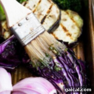 A close-up of a brush applying a flavorful marinade to cooked food.