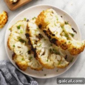 A white plate topped with roasted cauliflower florets next to a wooden cutting board, inviting a taste.