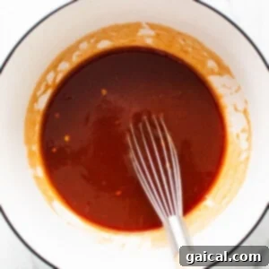 Dynamite Chicken Thighs 4 bbq sauce in a bowl with a whisk.