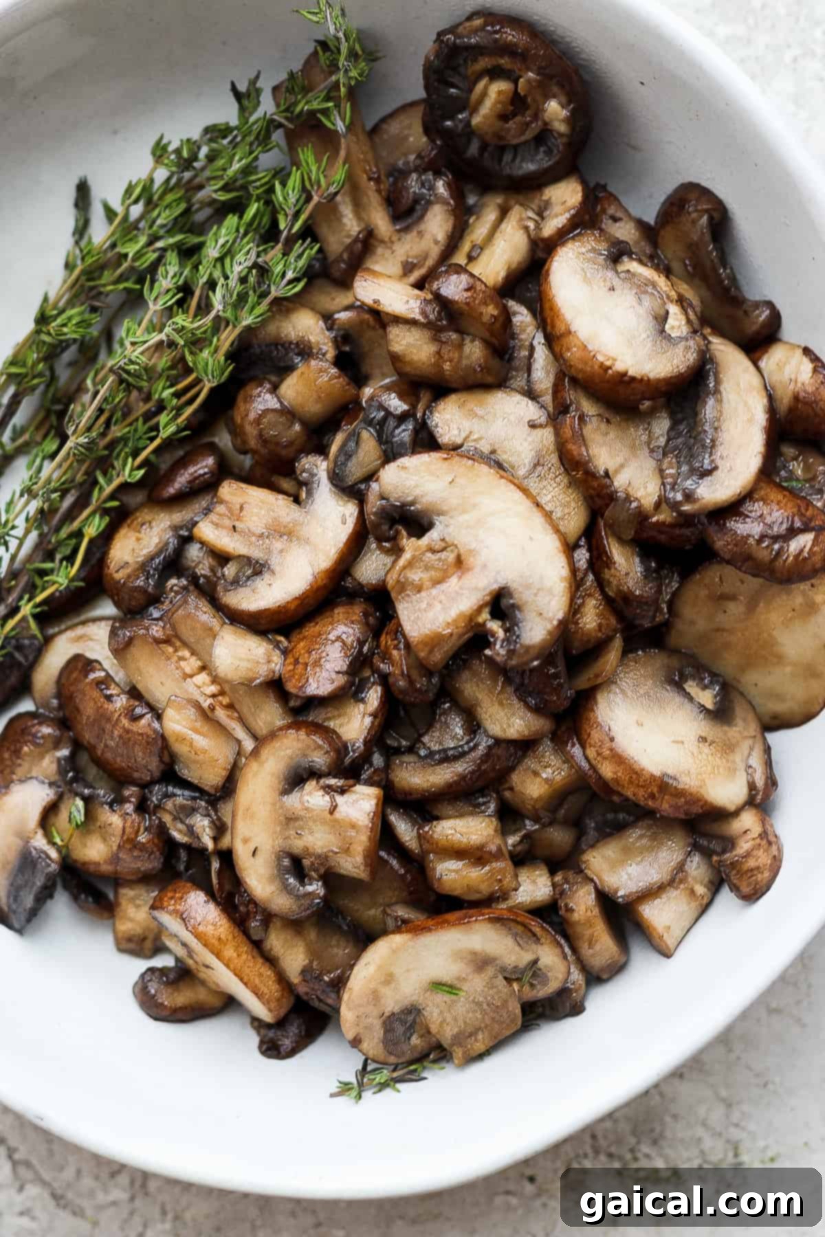 mushrooms in a white bowl with a sprig of thyme.