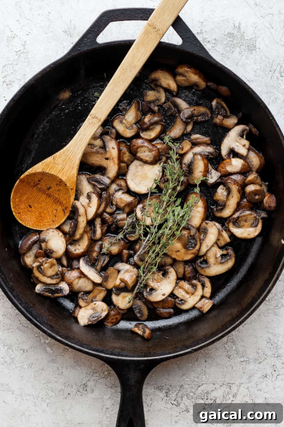 mushrooms in a skillet with a wooden spoon.