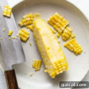 Sunshine Corn Salsa 7 Fresh corn kernels being sliced off the cob with a knife.